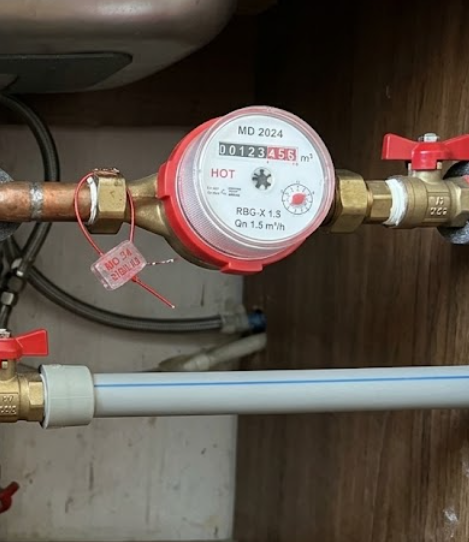 Contoare de apă rece și caldă montate sub chiuveta unui apartament, cu sigiliile vizibile